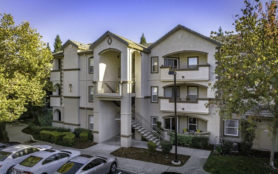 the view of an apartment building with a parking lot