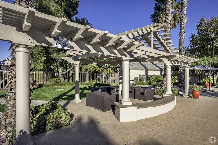a seating area under a white pergola in a garden