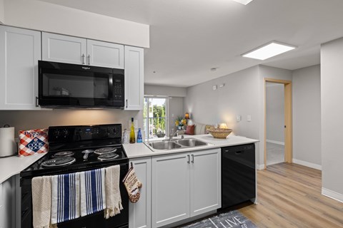 A kitchen with black appliances and white cabinets.