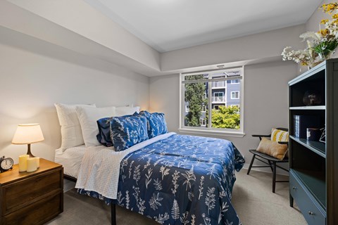 A bedroom with a bed and a window showing a view of a building.