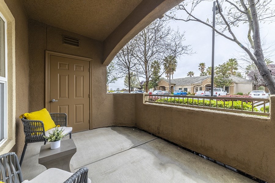 the front porch of a house with chairs and a table and a door
