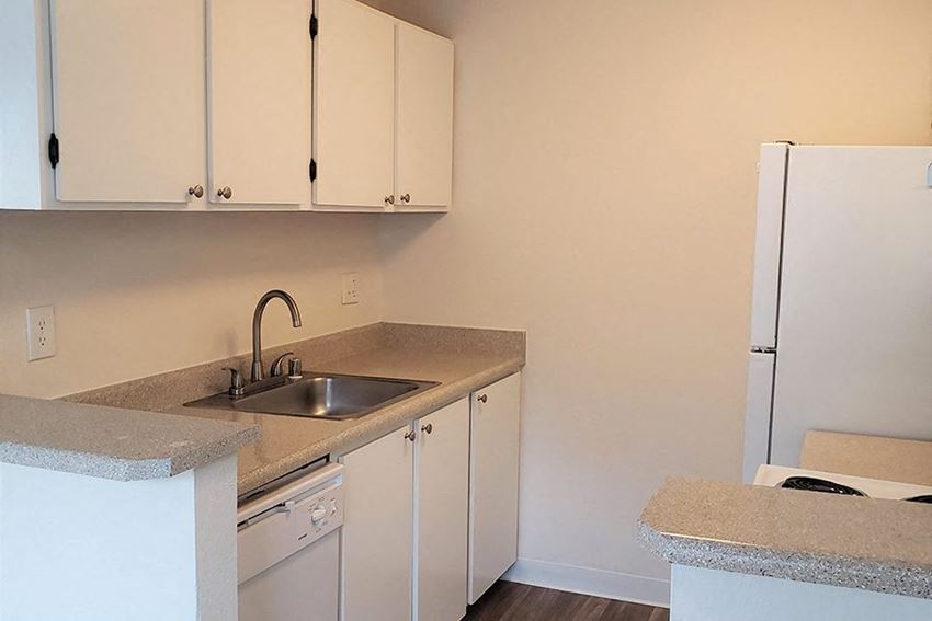 Des Moines Apartments - Marina Club - Kitchen Area with White Cabinetry, White Appliances, and Granite-Style Countertops