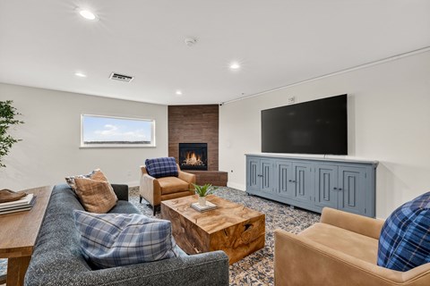A living room with a grey couch, a wooden coffee table, a fireplace, and a TV on a cabinet.