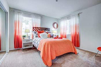 A bedroom with a bed covered in an orange blanket.