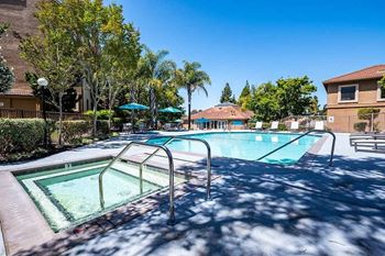 A swimming pool surrounded by trees and a building in the background.