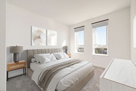 A bedroom with a large bed, a nightstand with a lamp, and a window with a view.