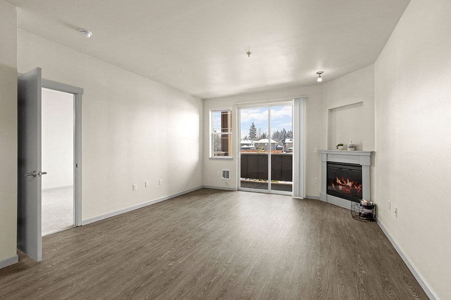 South Hill Puyallup, WA Apartments. - Bella on Canyon - Living Room with Wood-Style Flooring, Fireplace, Small Window, and Large Sliding Glass Door that Leads to a Patio