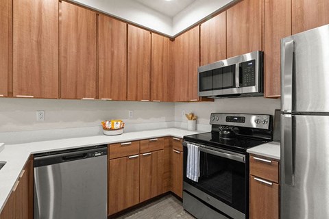 Apartment South Hill Puyallup, WA. - Bella on Canyon - Kitchen with White Countertops, Stainless Steel Appliances, and Wood-Style Cabinetry
