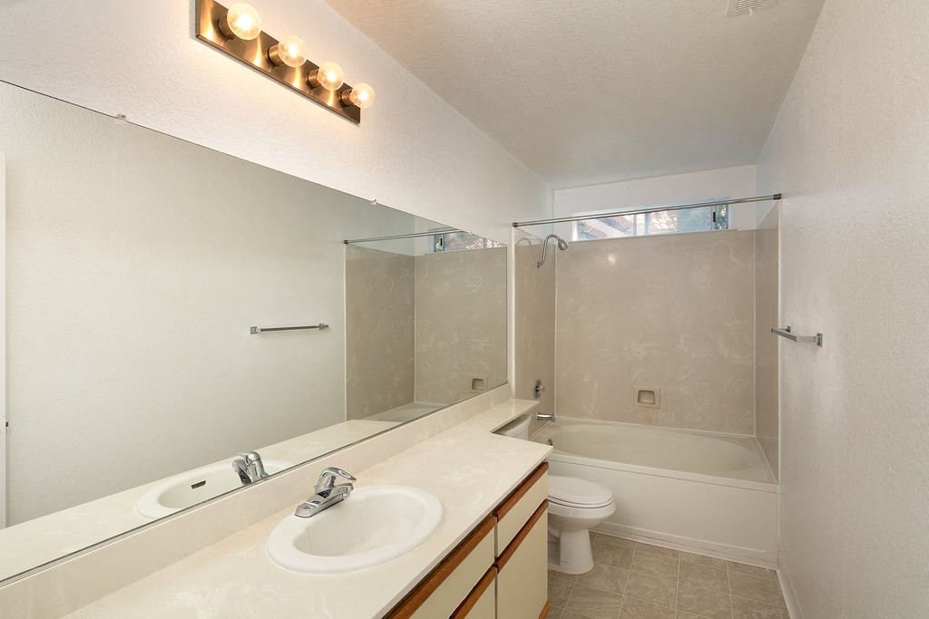 Bathroom with Large Vanity Mirror, Bulb Lights, and Tile Shower Backsplash at Laurel Creek, Fairfield, California