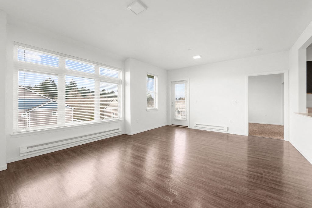 a bedroom with a large window and hardwood floors