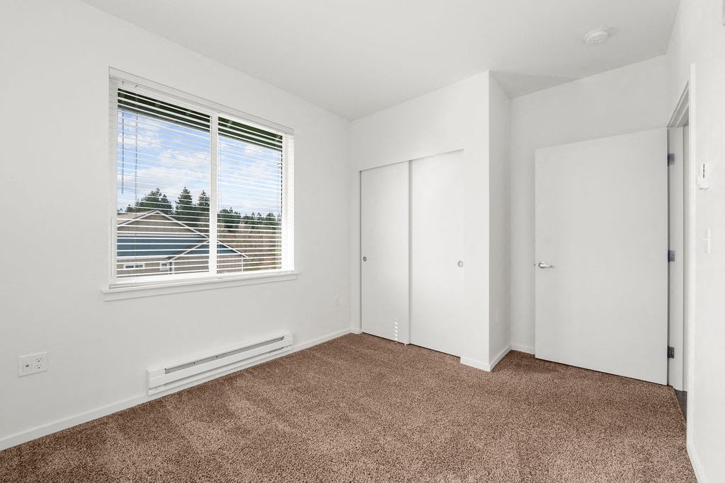 a bedroom with a large window and white walls