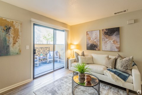 A living room with a white couch and a painting on the wall.