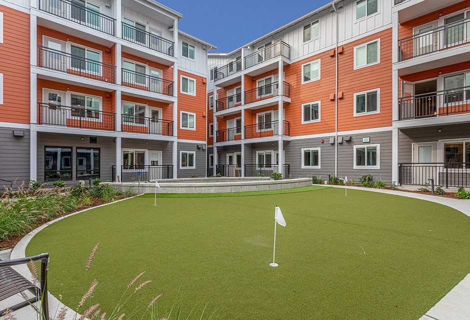 Senior Living In Arlington - Small Golf Area With Seating In Between Apartment Building