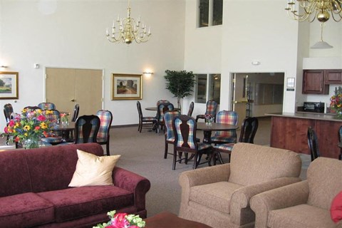 A living room with a red couch and a chandelier.