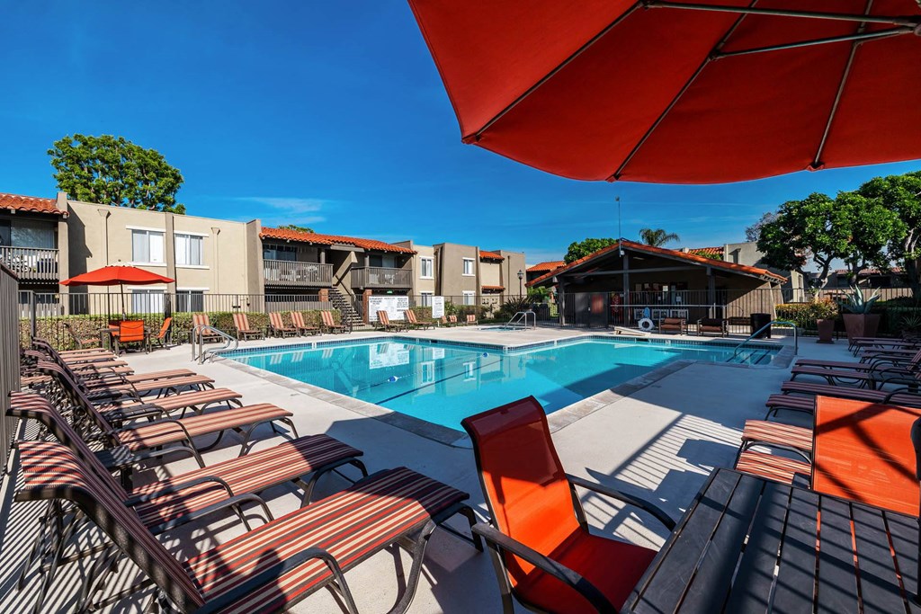 a pool with chairs and an umbrella next to a swimming pool