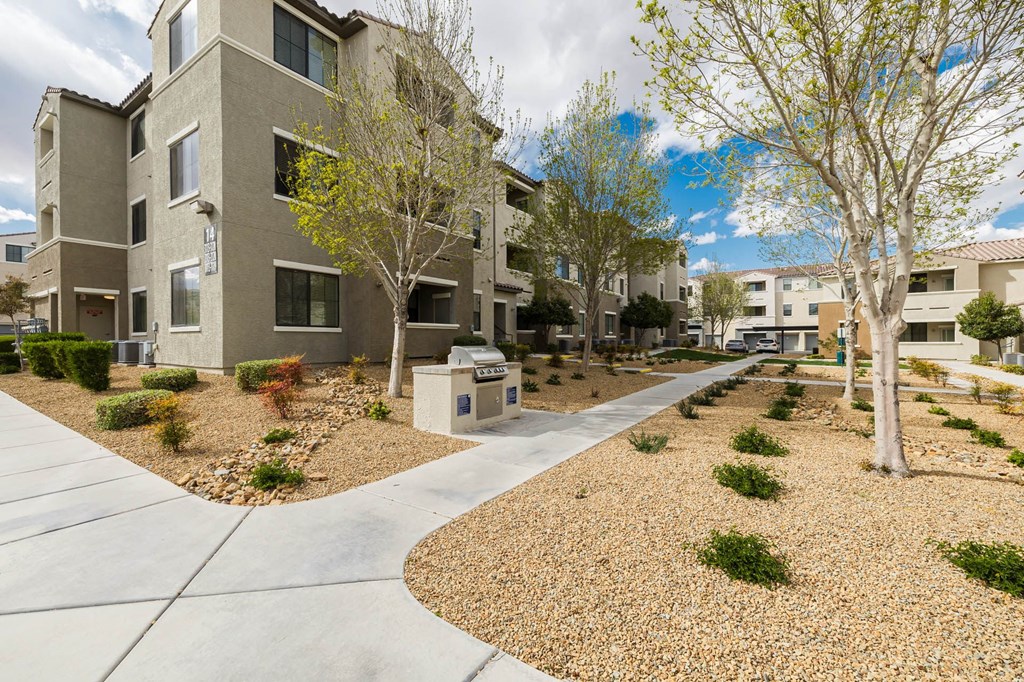 an exterior view of an apartment complex with trees and a sidewalk at CHANDLER APARTMENT HOMES, Las Vegas, NV, 89139
