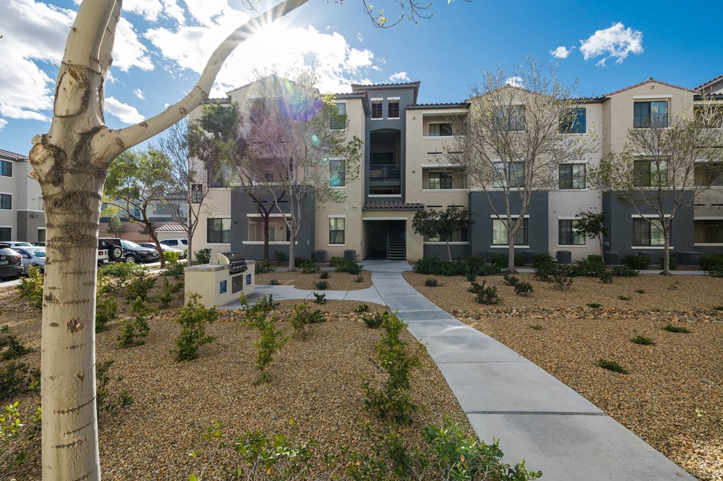 an exterior view of an apartment complex with a sidewalk and a tree at CHANDLER APARTMENT HOMES, Las Vegas, NV, 89139