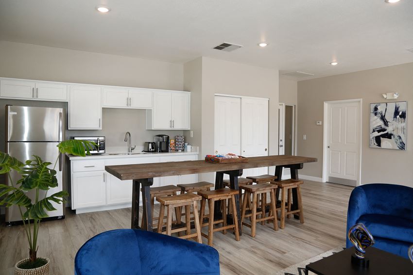 a kitchen and living room with a large wooden table and blue chairs