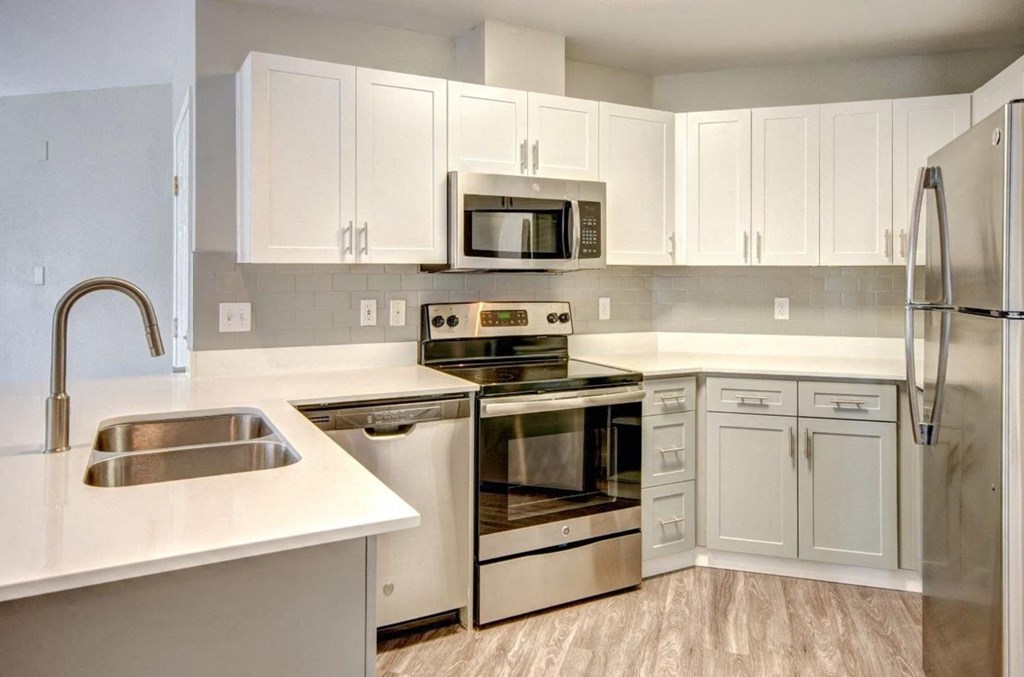 Dupont Apartments - Clock Tower Village - Kitchen with Stainless Steel Appliances, Double Sinks, White Cabinets, and Wood-Style Flooring
