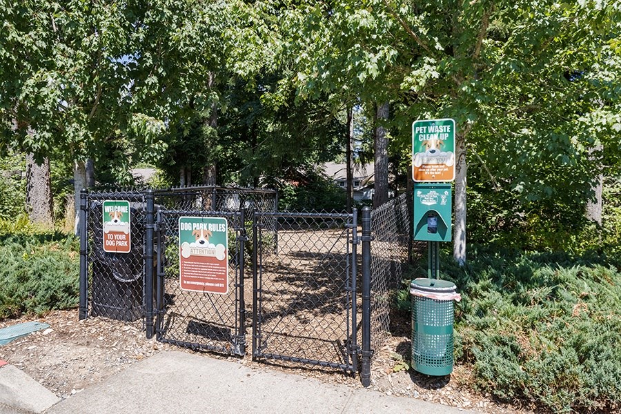 One Bedroom Apartments in Olympia, WA - Yauger Park Villas - Spacious Bark Park with Black Fence, Wood Chips, Trash Can, and Trash Bags
