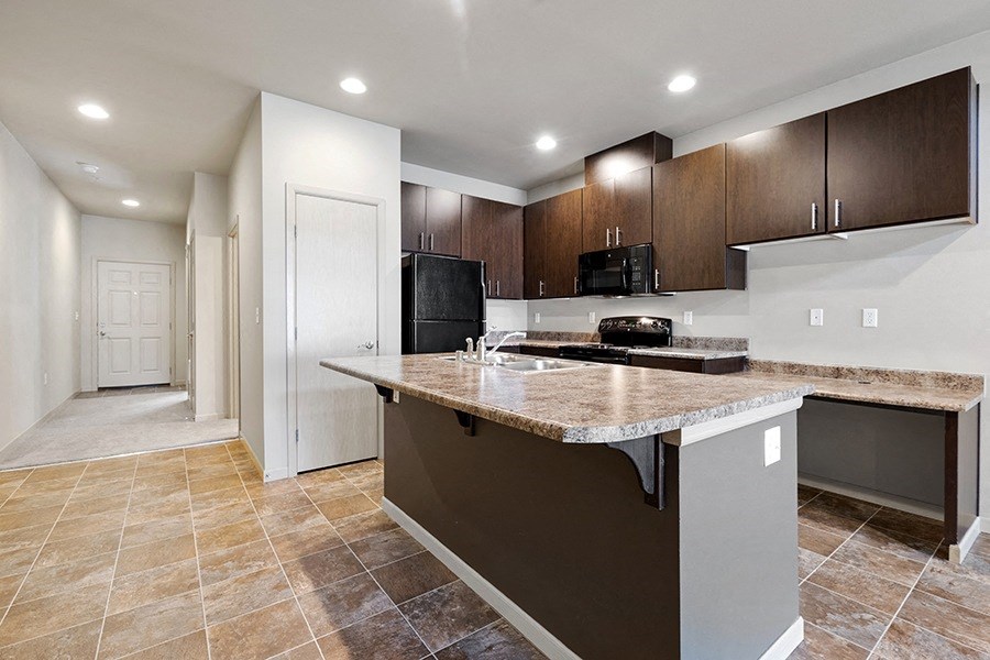Apartments for Rent in Olympia WA - Yauger Park Villas - Modern Kitchen with Tiled Flooring, Granite Countertops, and Dark Wood-Style Cabinets
