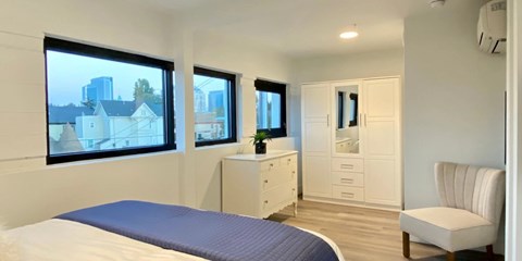 A bedroom with a bed, dresser, and chair.