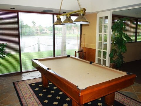 a pool table in a living room with a window