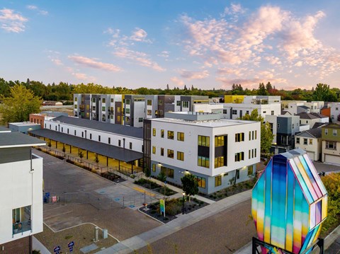 A colorful building with a white and yellow exterior is surrounded by other buildings and a playground.
