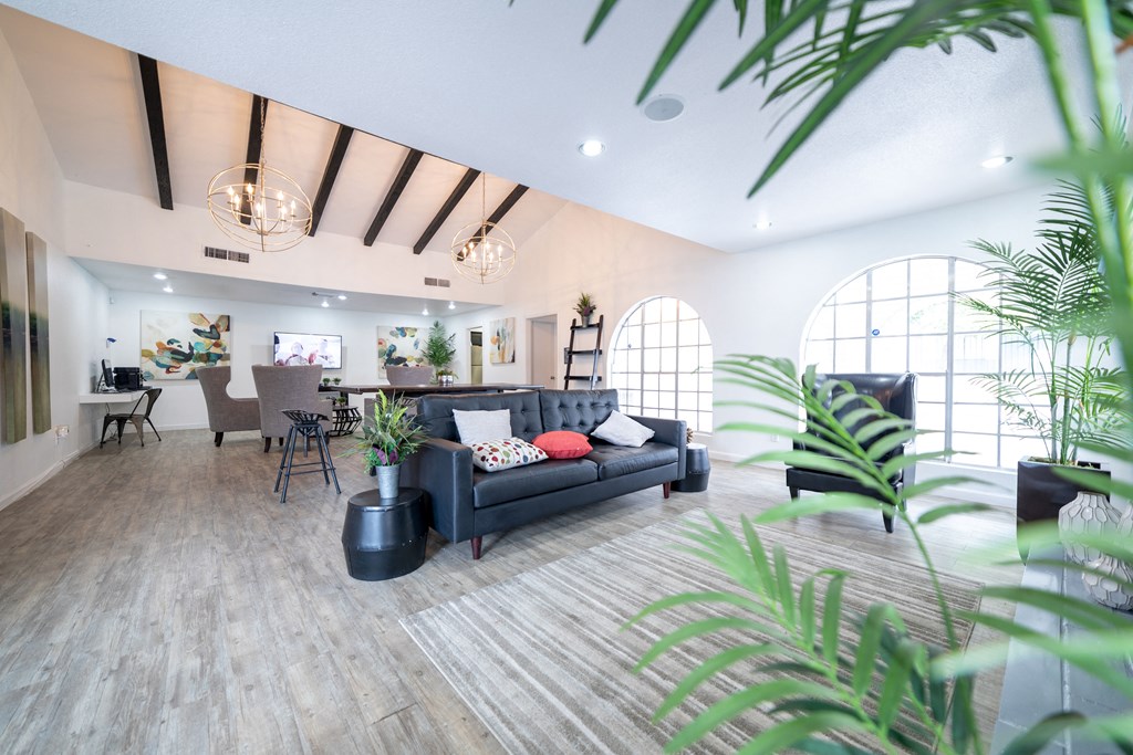a living room with a black couch and a dining room in the background at DESERT PEAKS, EL PASO, Texas