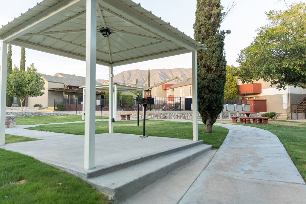 a white pavilion sits in the middle of a grassy area with houses in the background at DESERT PEAKS, EL PASO Texas