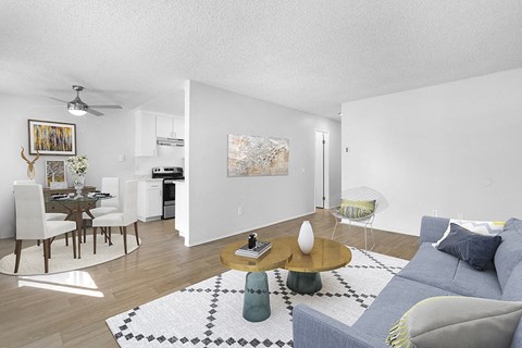 A living room with a grey couch, a coffee table, and a dining table with chairs.