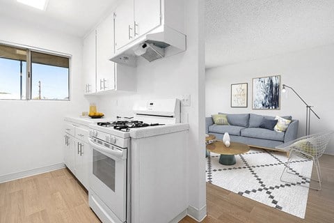 A modern kitchen with a white stove and a grey sofa in the living room.