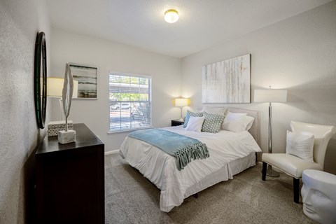 a bedroom with a bed and a chair in a room