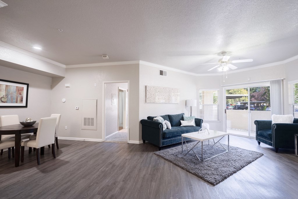 a living and dining room area with a couch table and chairs and a ceiling fan