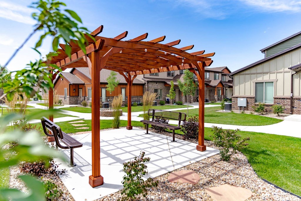 a wooden pergola with a bench in a courtyard at Arcadia Townhomes, Roy