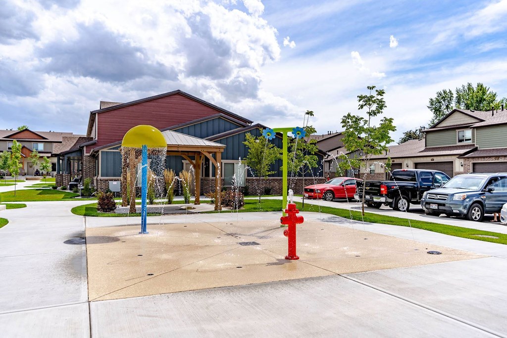 a red fire hydrant on a sidewalk in front of a building at Arcadia Townhomes, Roy, UT