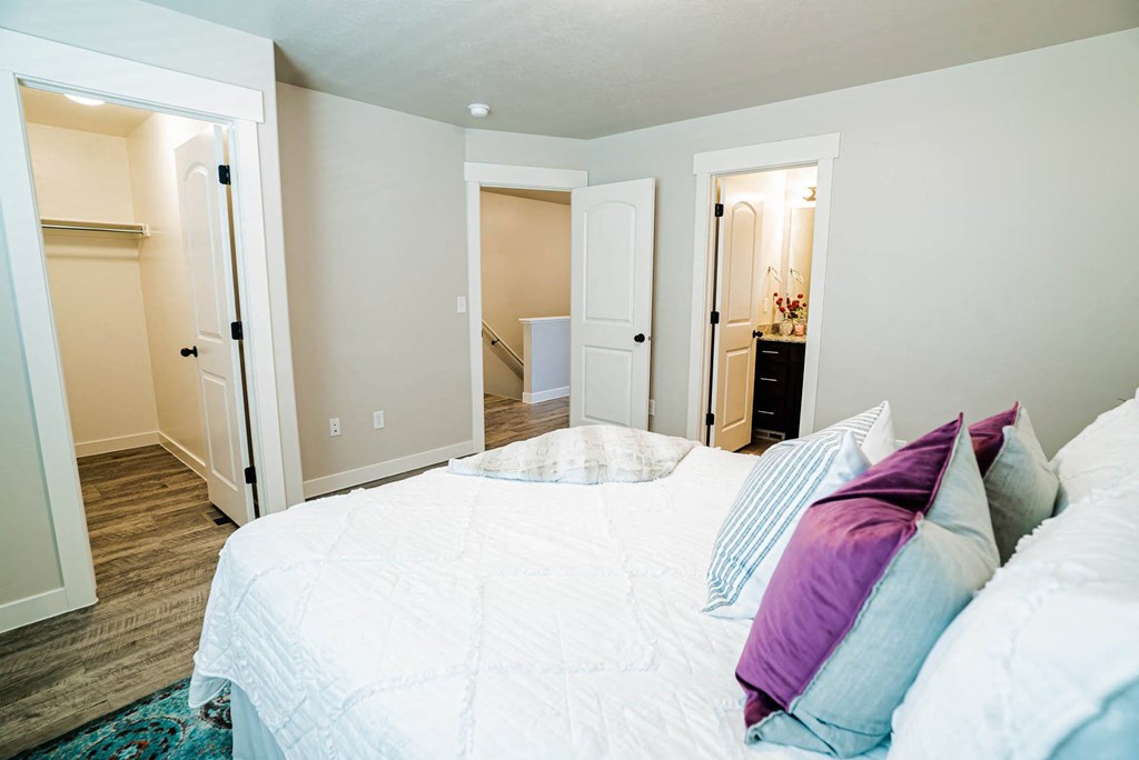 a bedroom with a large bed and a door to a bathroom at Arcadia Townhomes, Roy Utah