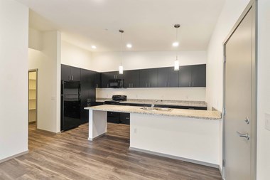 Crescent Point living area with plank flooring and kitchen with dark cabinetry