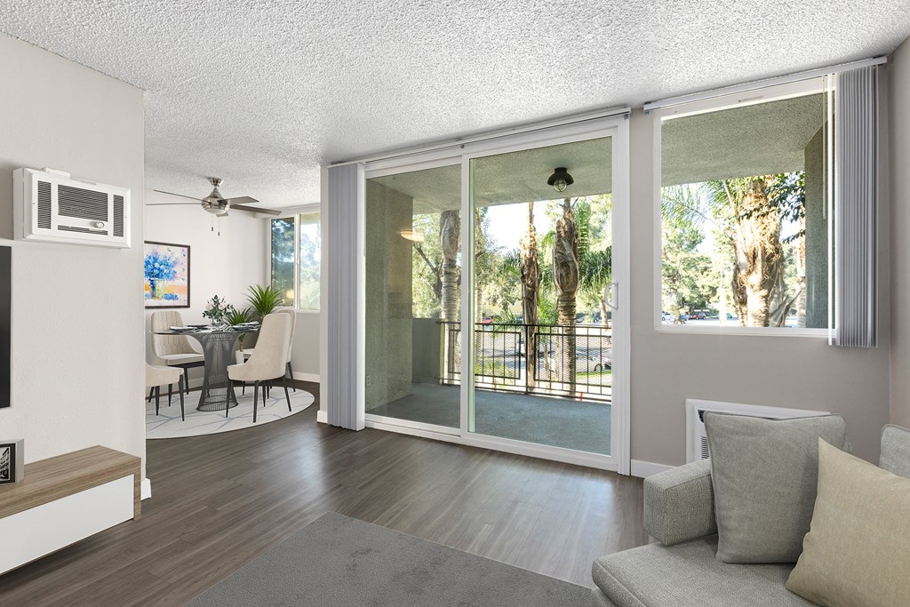 a living room with a couch and a chair and a sliding glass door leading to a balcony