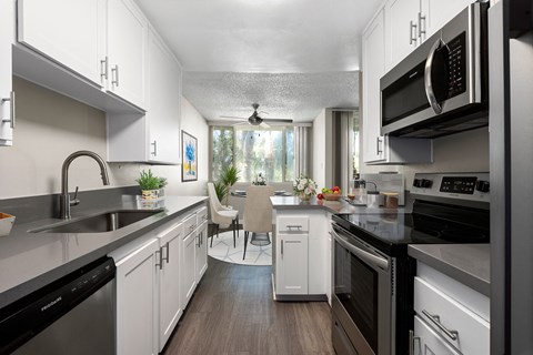 a kitchen with white cabinets and stainless steel appliances and a dining room with a window