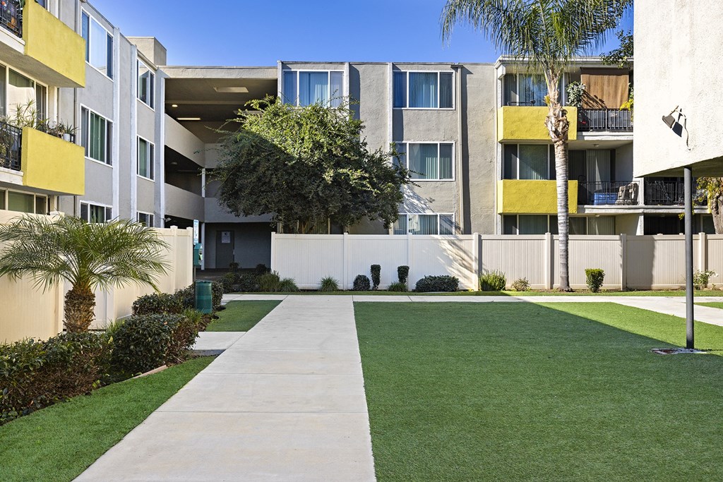 a picture of an apartment complex with green grass and palm trees