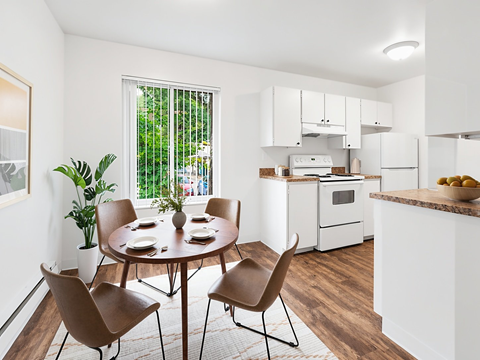 A dining room with a table set for four and chairs around it.