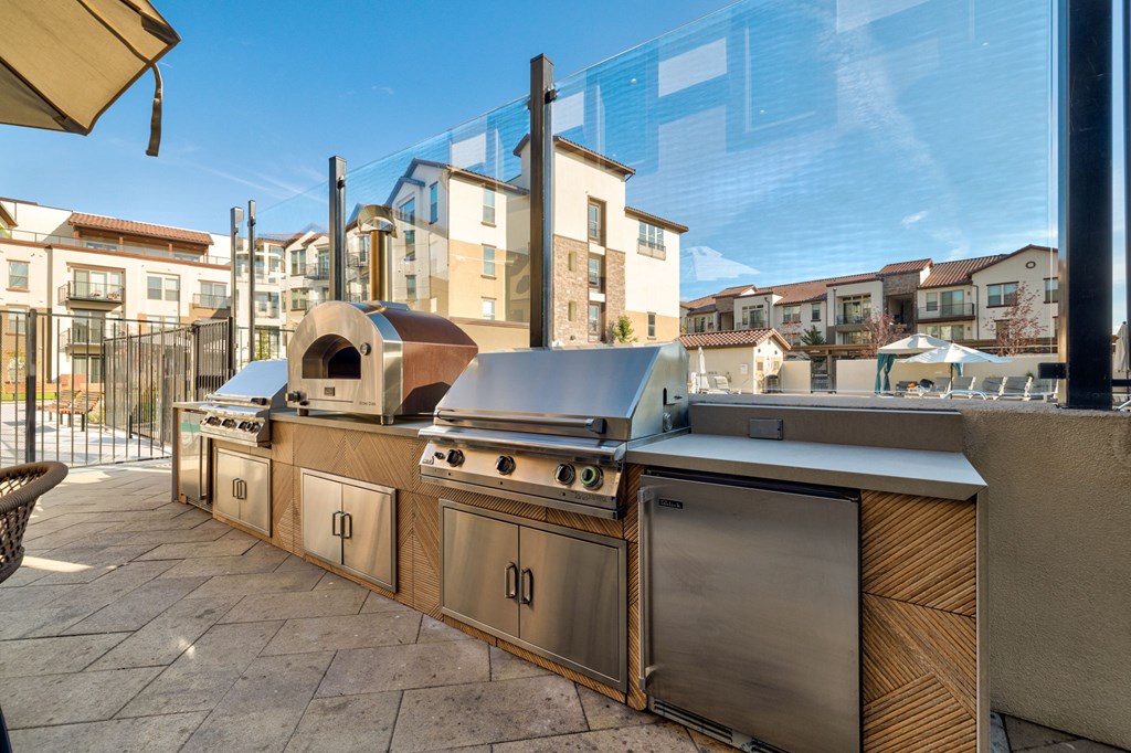 A row of outdoor kitchen appliances are lined up on a patio.