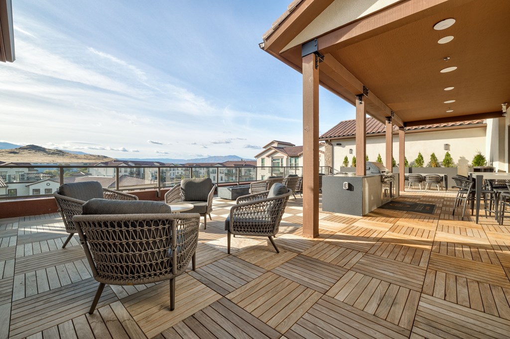 A patio with chairs and a table is covered with a roof.