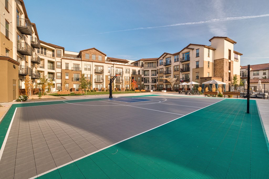 A basketball court in front of apartment buildings.