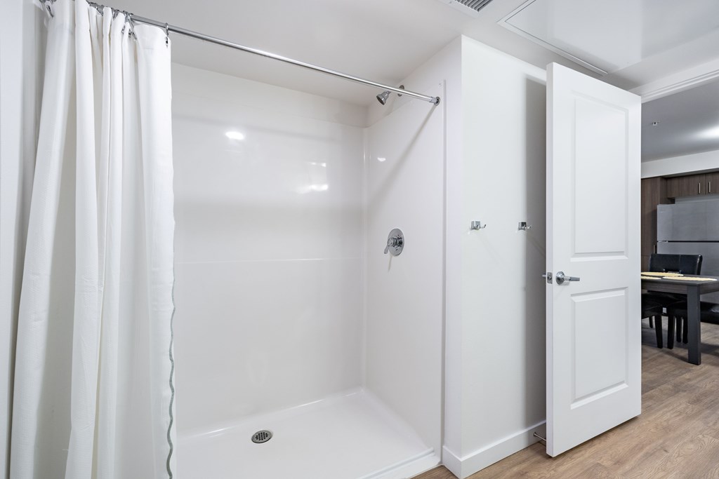 A white bathroom with a shower and a sink.at Traditions at Hazelwood, Portland, OR