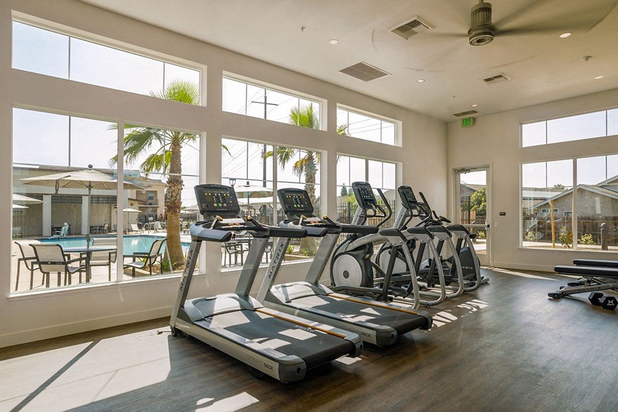 Apartments in Chico for Rent - Community Fitness Center with Multiple Treadmills, a Wall of Windows, and a Ceiling Fan