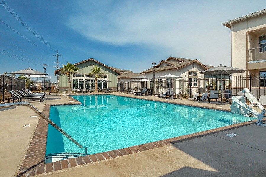 Apartments For Rent In Chico - Gated Pool With Cabanas, Lounge Chairs, Umbrellas, And Resident Club House In The Background.