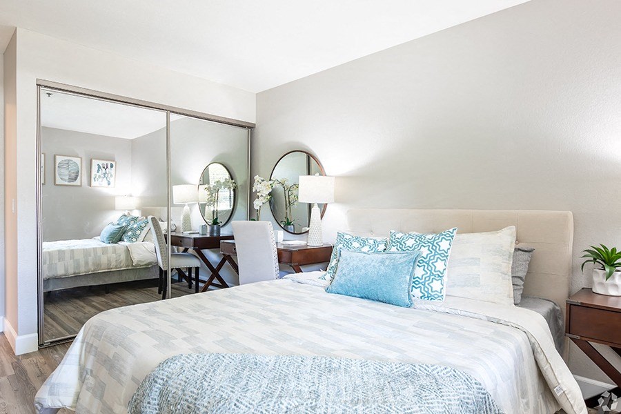 One-Bedroom Apartments in Pleasant Hill, CA - Ellinwood - Bedroom with Plush Bedding, Study Desk, and Sliding Mirror Closet Door