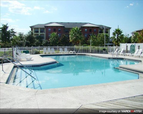A swimming pool with a metal railing and chairs around it.